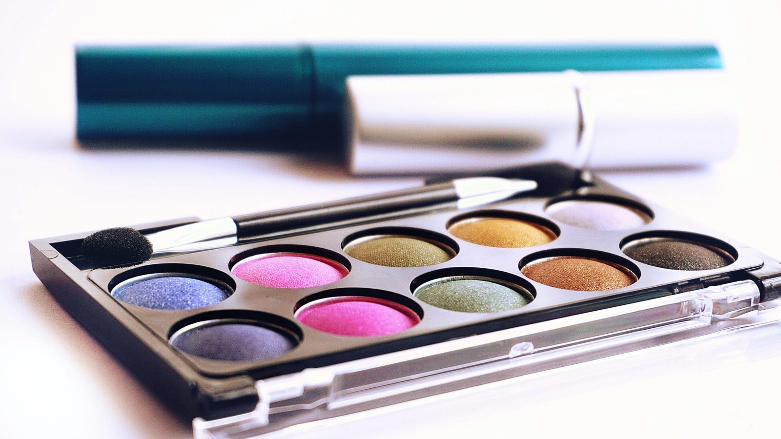 Close-up of colorful eyeshadow palette with brush, ideal for fashion and beauty themes.